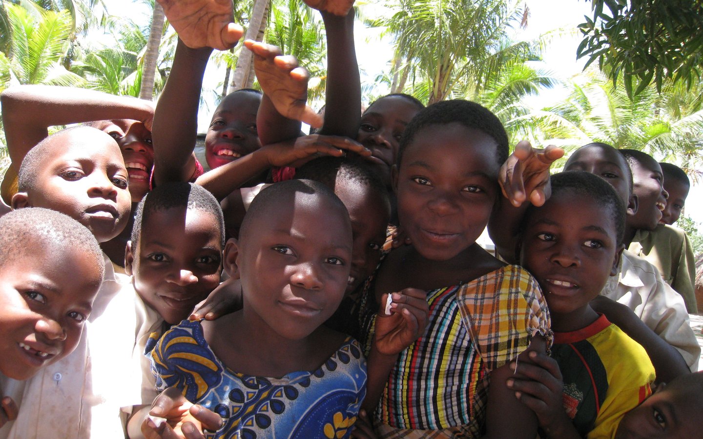 A group of children, bunched together looking at the camera and smiling